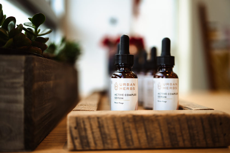 Business Photography, Bottles capped with dropper lids sit in a row on a store table, the read "Urban Herbs Active Complex Serum"