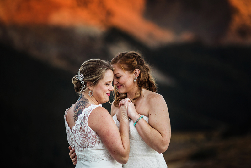 Elopement photographer, bride and bride hold each other close before the red mountains as the sun sets