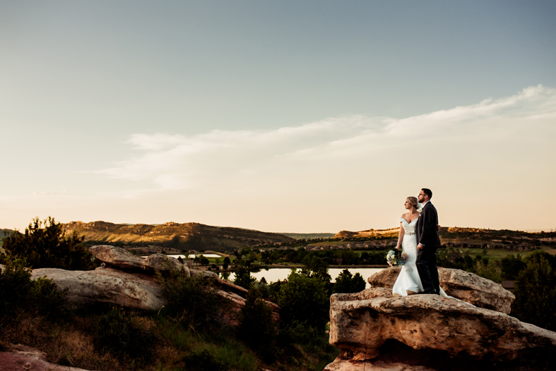 Elopement Photographer, Bride and groom stand on a large rock in the hillside dressed in full wedding attire