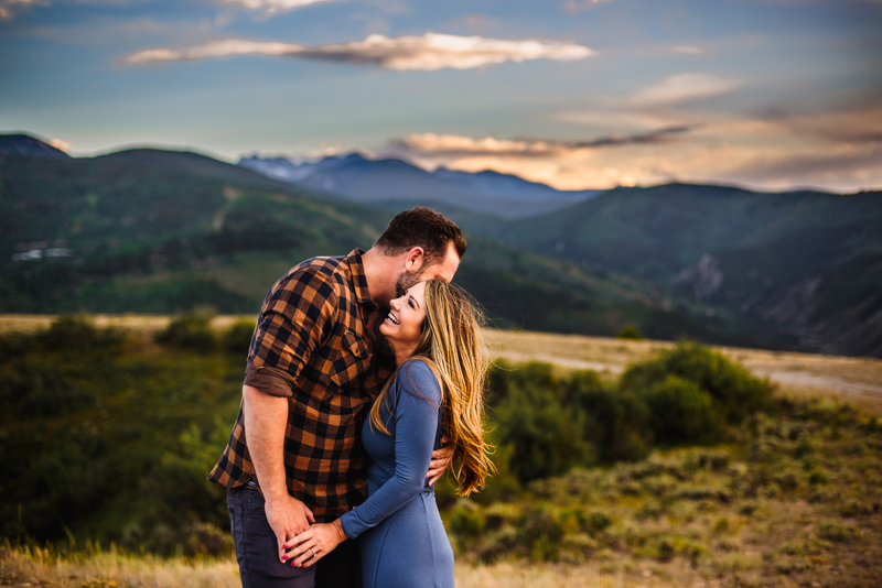 Elopement Photographer, man in flannel shirt holds a woman close, they are in standing near green hillsides